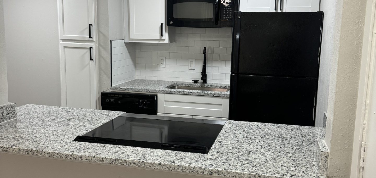 a kitchen with a black stove and white cabinets at The Villa La Paz Apartments